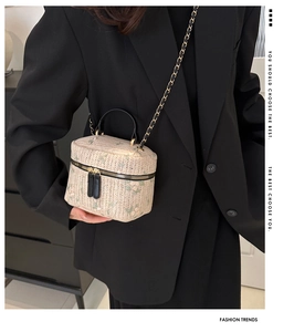 Close-up of woven straw handbag with green floral embroidery and black leather strap