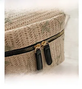 Close-up of green leaf embroidery on apricot lace fabric with dual gold metal zippers