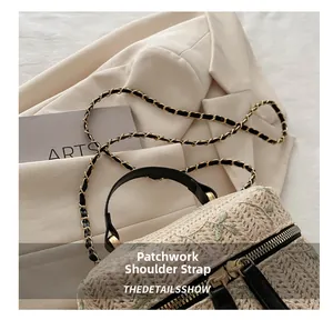 Close-up of woven beige handbag featuring green leaf embroidery and metal dual zippers