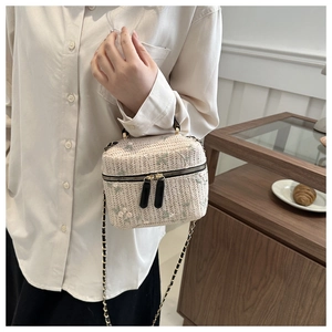 Detail of straw woven bucket bag with floral embroidery and leather chain strap