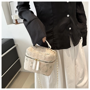 Detail of beige woven box bag featuring delicate green floral embroidery and dual zippers