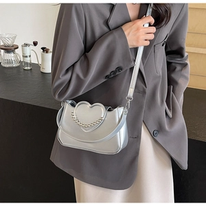 Silver metallic heart shoulder bag with beaded trim styled on a casual modern outfit