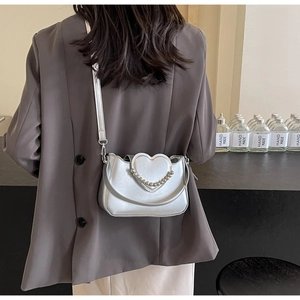 Detail of silver heart-shaped crossbody bag with metallic bead trim and slim strap