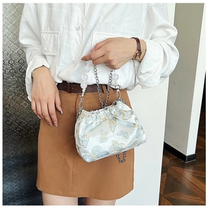 Detail of white satin bucket bag with blue butterfly embroidery and pearl bead handle