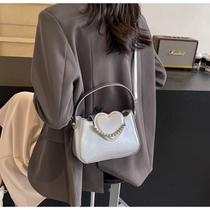 Silver glossy shoulder bag with 3D heart design and bead chain shown in a lifestyle setting