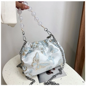 Detail of light blue satin bucket bag with gold butterfly embroidery and beaded handle
