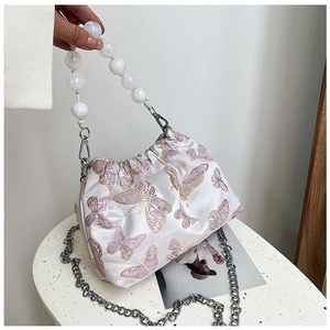 Detail of white satin bucket bag with butterfly embroidery and pearly cloud bead handle