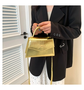 Détail du mini sac à main doré métallisé avec nœud tissé et poignée supérieure élégante