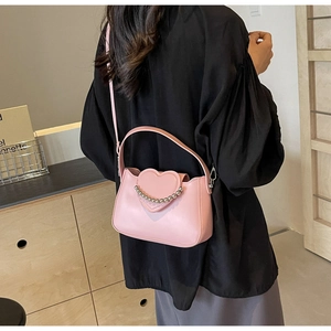 Detail of pink heart-shaped handbag with silver beaded chain and premium leather texture