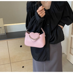 Detail of pink heart-shaped handbag with silver beaded trim and refined texture