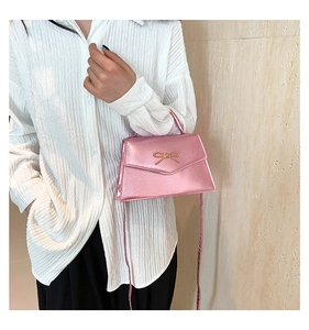 Détail d'un mini sac à main rose métallisé orné d'une boucle en nœud doré élégante