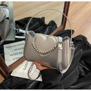 Detailed view of silver metallic bag featuring a heart ornament and beaded trim detailing