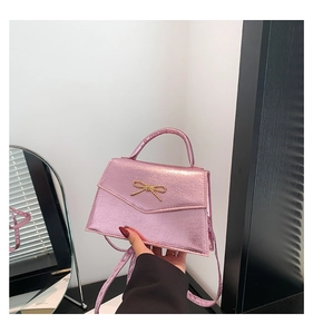 Détail du mini sac à bandoulière rose métallisé avec nœud doré et cuir PU texturé