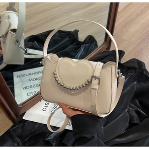 Close-up of cream chain handbag featuring 3D heart design and silver beaded accents