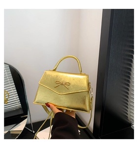 Détail d'un mini sac bandoulière doré métallisé avec un nœud décoratif en métal