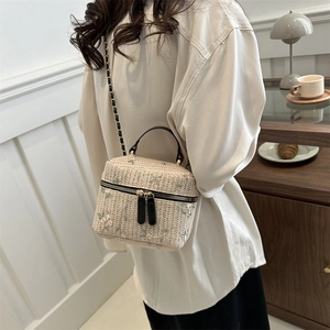 Straw box bucket bag with floral embroidery and gold chain strap on female model
