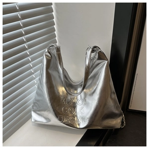 Detailed macro view of the silver metallic tote bag with MUDOU COLO DESING relief