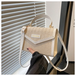 Detail of woven straw mini bag with cream leather trim and gold 'FASHION' lettering