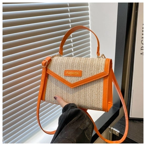 Detail of trendy woven straw handbag with bright orange faux leather trim and gold hardware