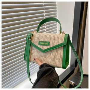 Detail of woven straw handbag featuring green leather trim and gold fashion hardware