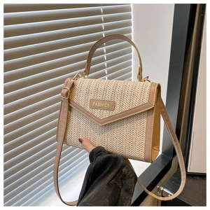 Close-up of the woven texture and golden fashion label on a beige crossbody bag
