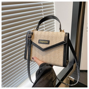Detail of woven straw handbag with black leather trim and elegant gold hardware