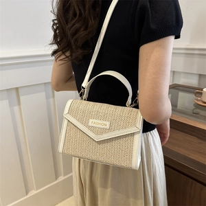 Fashionable woven straw crossbody bag with white PU trim and adjustable strap on a model