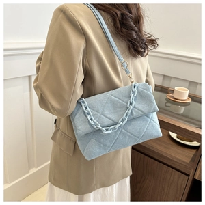 Close-up of light blue quilted envelope bag with matte chain strap shown on a model