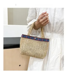 Detail of handwoven straw tote with pink and blue geometric patterned webbing and metal buckle
