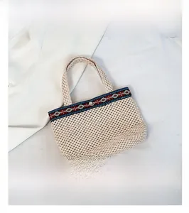Detail of hand-woven beige tote bag featuring ethnic geometric ribbon and silver metal snap