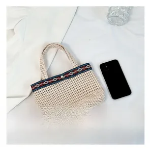 Close-up of woven straw envelope bag with ethnic style trim and metal button closure