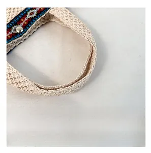 Close-up of woven straw handbag handle with colorful ethnic pattern and silver metal snap