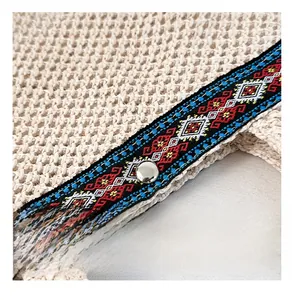 Close-up of crochet texture with colorful ethnic embroidery and silver metal snap button