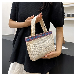 Detail of woven straw handbag with ethnic embroidery trim and metal magnetic clasp