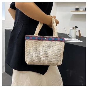 Detail of hand-woven straw tote bag with ethnic geometric strap and silver snap closure