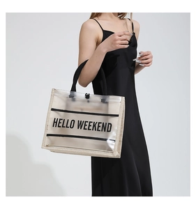 Detail of clear PVC tote bag featuring black HELLO WEEKEND text and round handles