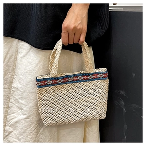 Close-up of hand-woven straw clutch with ethnic geometric embroidery and metal snap