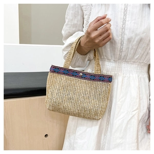 Detailed texture of handwoven straw clutch featuring bohemian colorful ribbon trim