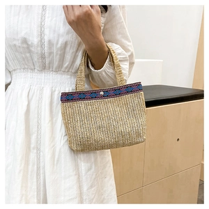 Detail of woven straw handbag showing textured chevron pattern and ethnic trim with snap