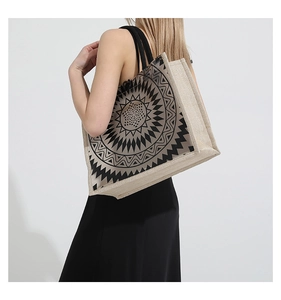 Detail view of large jute tote bag with black mandala print worn by model on shoulder