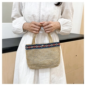 Close-up of bohemian embroidered strap on a handmade woven straw envelope clutch bag