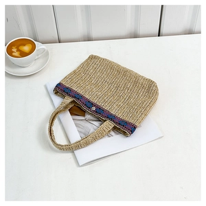 Detailed close-up of woven straw handbag with ethnic embroidery and elegant handle