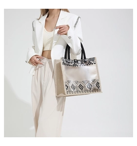 Close-up of a large tote bag with PVC geometric pattern and natural straw side texture