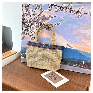 Detail of hand-woven envelope bag with ethnic embroidery trim on a wooden table