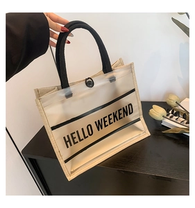 Detail shot of a transparent PVC tote bag with canvas insert and Hello Weekend text