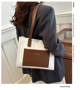 Detail shot of a woven white tote bag with brown fashion pocket and long shoulder straps