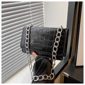 Detail of glossy black crocodile embossed mini bag with thick silver chain strap