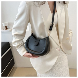 Detail of a black half-moon saddle bag with a matte leather finish and gold hardware