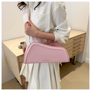 Side view of a light pink asymmetric shoulder bag showing its stylish curved silhouette