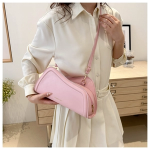 Sac bandoulière rose chic avec lettrage doré porté par un mannequin stylé
